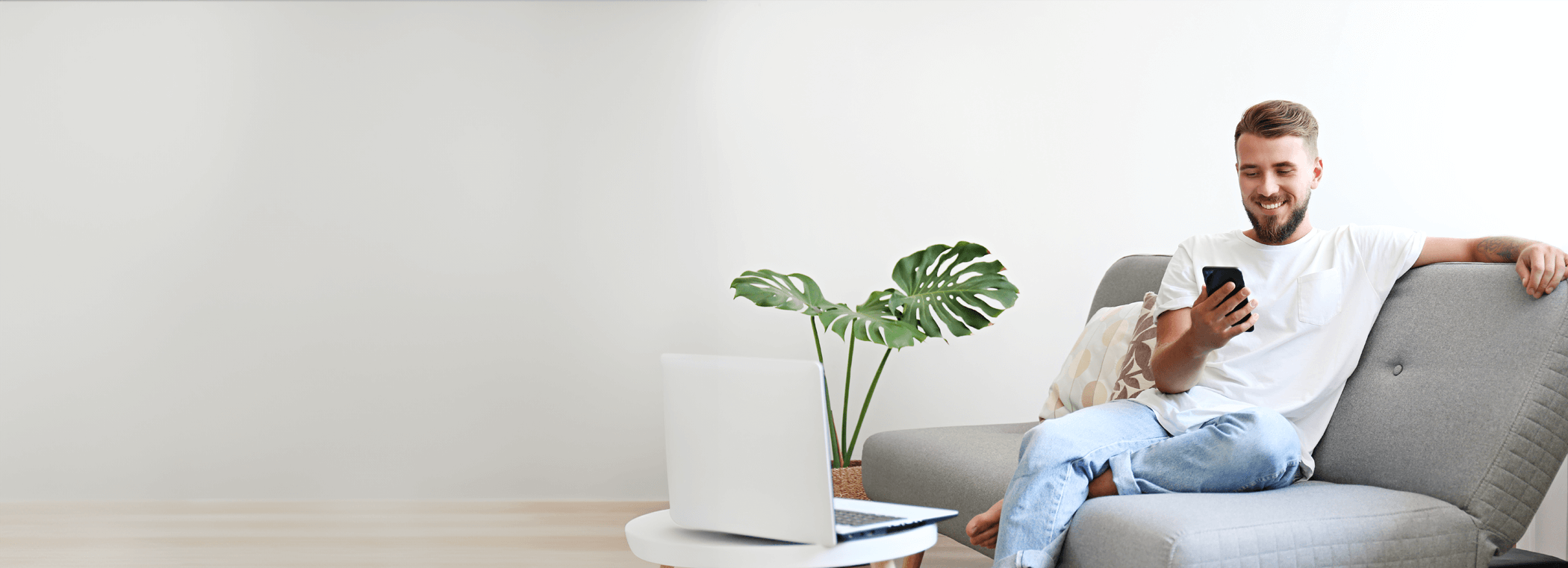 A man is sitting on the couch with a mobile phone in his hand.